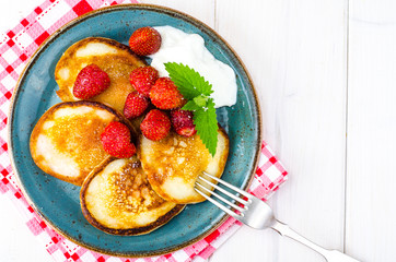Delicious sweet fried pancakes with sugar and strawberries