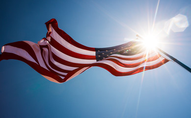 Sunburst over American flag against blue sky