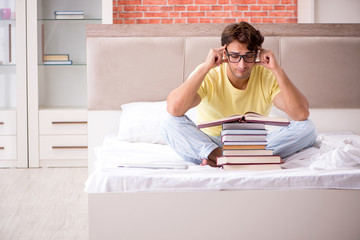 Young student studying in bed for exams