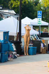 Nude female  mannequin on street with boxes around it.