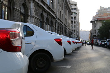Row of white cars parked on street