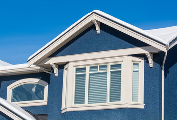 A perfect neighborhood. Top of new luxury residential house in snow. North American family house on winter sunny day