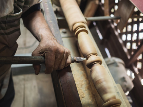 Hands of carpenter turning wood on lathe