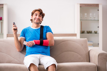Fototapeta na wymiar Young man with injured arm sitting on the sofa 