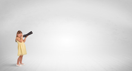 Cute little girl looking through spyglass to an empty space
