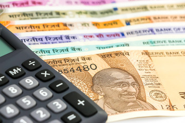 Close up view of calculator over brand new indian 10, 50, 100, 200, 500 and 2000 rupees banknotes....