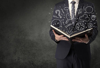 Businessman holding book with doodle drawings and signs.