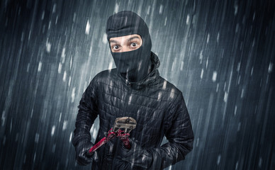 Burglar in action in black clothes with rainy concept. 
