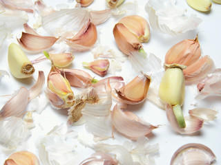 Garlic slices and garlic husks on a white background.