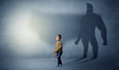 Cute kid in a room with plush on his hand and hero shadow on his background
