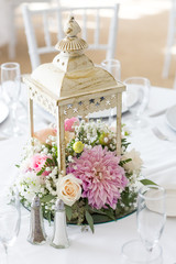 Closeup of flower-filled lamp as a center piece on a table.