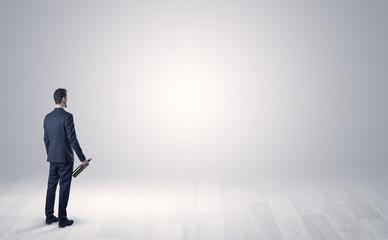 Man standing with his back in an empty room with object in his hand