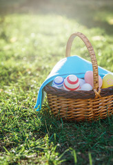  Hand painted Easter eggs in rattan basket on  green grass with blue towel.  Traditional decoration for Easter at sunny spring day. Eggs hunt