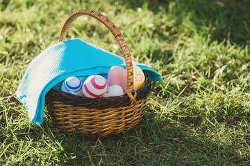  Hand painted Easter eggs in rattan basket on  green grass with blue towel.  Traditional decoration...