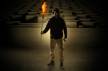 Ugly, aberrant man coming out from the labyrinth with burning flambeau on his hand
