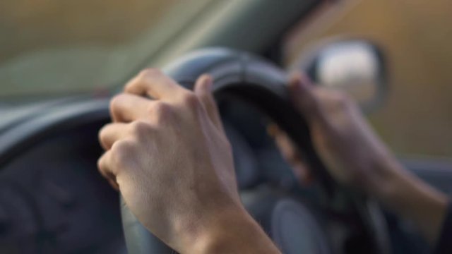 Slowmotion shot of hands of a mand riving a car on a car travel