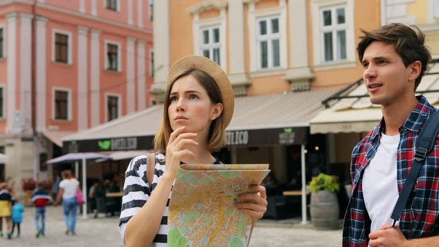 Tourist young woman wearing a hat and a young caucasian man in white T-shirt and a shirt visiting new city on vacation trip.