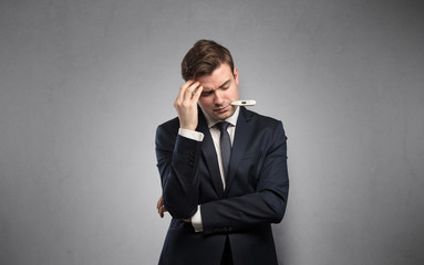 Young tired businessman with thermometer and copy space

