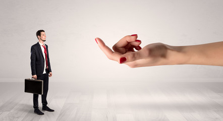 Businessman with kisses on his face in an empty space where a big hand baiting him
