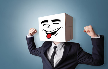 Young boy standing and gesturing with a cardboard box on his head
