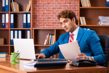 Young handsome employee sitting in the office  