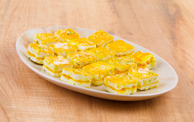 Paneer Burfi or Paneer Kesar Burfi is a Traditional Indian Mithai or Sweet Dish Prepared From Freshly Made Paneer, Mawa, Milk or Cottage Cheese on Wooden Background