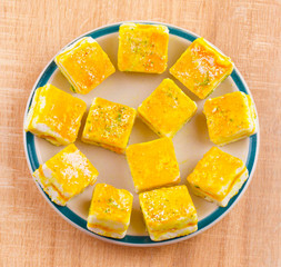 Paneer Burfi or Paneer Kesar Burfi is a Traditional Indian Mithai or Sweet Dish Prepared From Freshly Made Paneer, Mawa, Milk or Cottage Cheese on Wooden Background