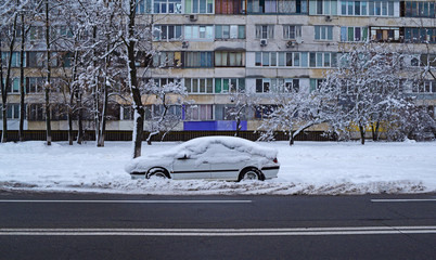 View of the car near the road in the winter snow city.