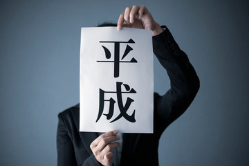 平成の文字を持つスーツの女性