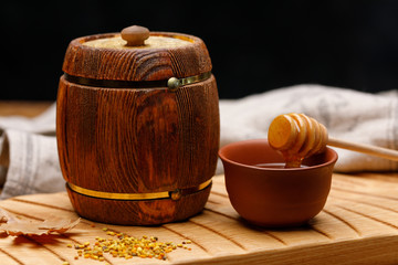 Wooden barrel with honey and a spoon on a wooden table. Barrel