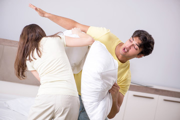 Wife and husband having pillow fight in bedroom