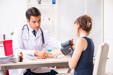 Young doctor checking woman's blood pressure