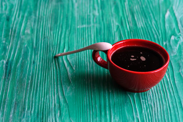 A cup of coffee on a green wooden background.