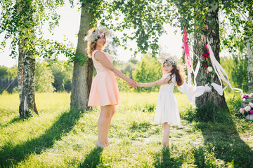 happy mother and daughter holding hands in the summer outdoors