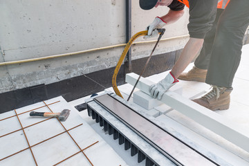 Waterproofing and thermal insulation of a terrace - roof. Professional worker, near a drain gully for drainage, is preparing a layer of extruded polystyrene insulating