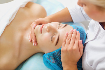 Obraz na płótnie Canvas Cosmetologist makes facial massage to a young woman.