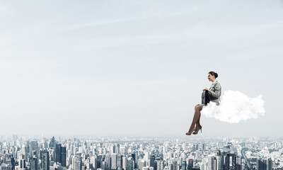 Businesswoman or accountant on cloud floating high above modern 
