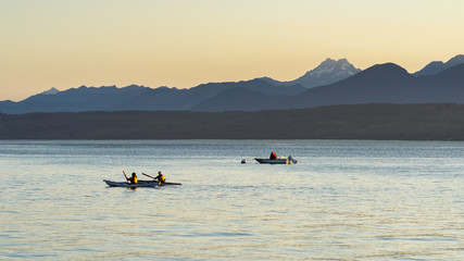 Couple kayaking in the Hood canal with Olympic National Park in the background
