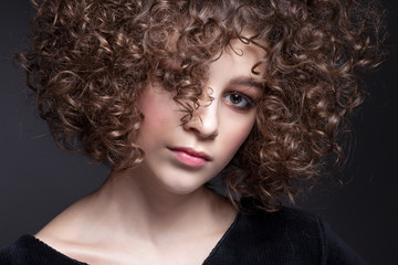 Fototapeta premium Portrait of a beautiful teen girl with natural make-up and afro curls.