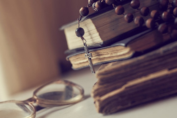 The rosary beads on Catholic Church liturgy books and old glasses on the side of them.