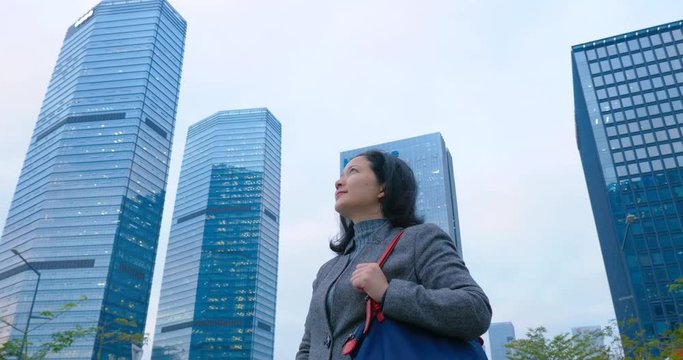 4k:chinese woman looking upward between morden skyscrapers,shenzhen china