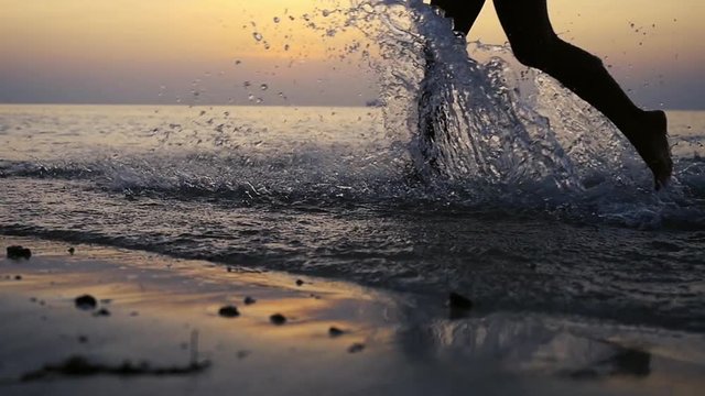 Female feet run in sunset sea close up in slow motion. 1920x1080