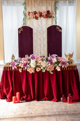 Festive table in red and gold colors decorated with flowers