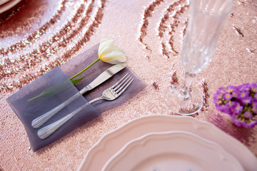 Served table with pink plates on pink tablecloths and Cutlery.