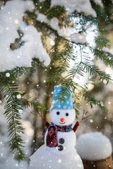 Happy snowman standing in winter christmas landscape. Snowman smiling standing in snow near spruce trees