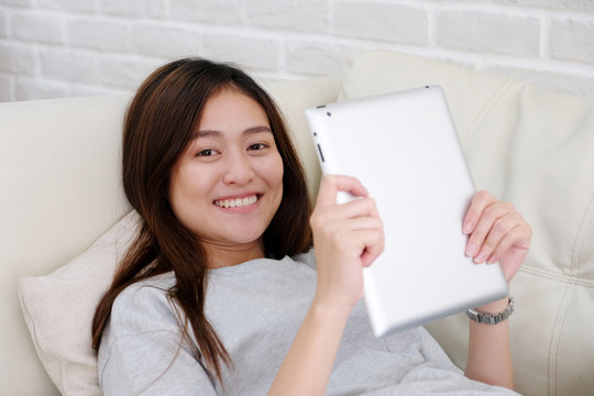 Young asian woman using tablet while sitting in sofa background, people and technology, lifestyle, adult online education, working from home