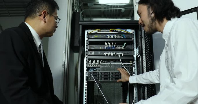 Asian Internet technician explain about modem cabinet to his boss, he fixing system, then they handshake, concept for Internet technician's work.