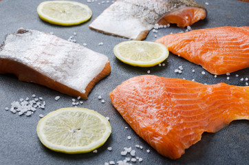 slices of salmon with lemon on black table