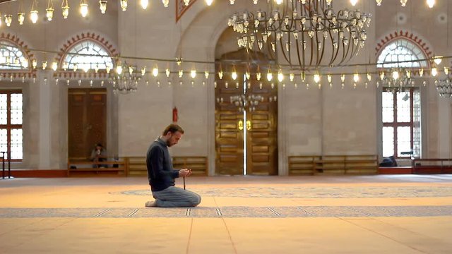 Muslim young male with rosary beads praying in mosque