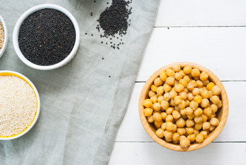 cooked chick pea and sesame seeds, hummus ingredients on cotton canvas, white wooden table background